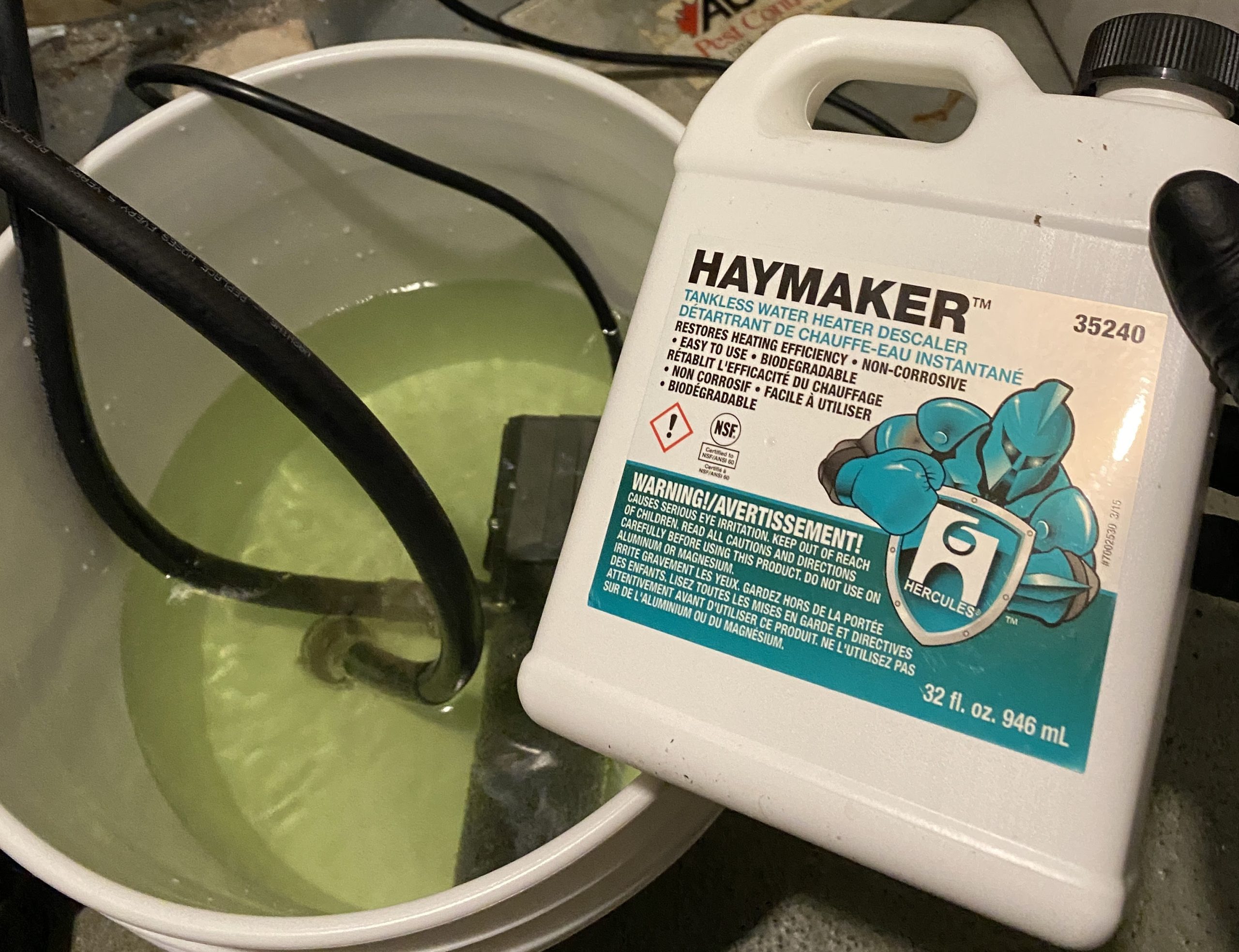 Haymaker descaler bottle beside flush bucket for tankless water heater in Greater Vancouver