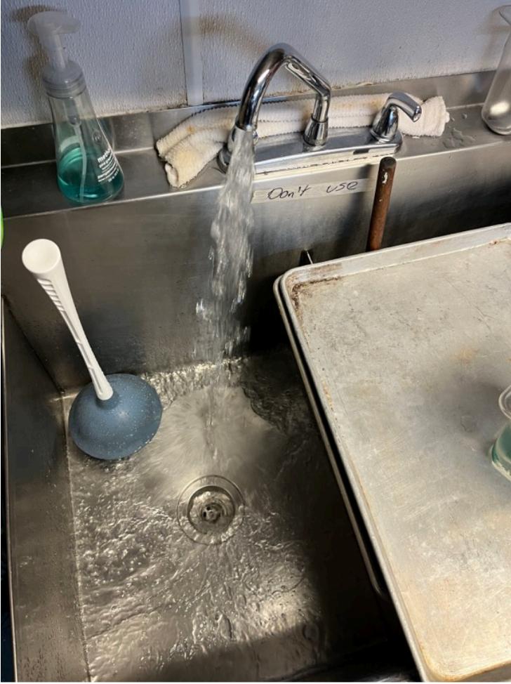 plunger in sink with running water test - commercial kitchen in maple ridge with dont use sign