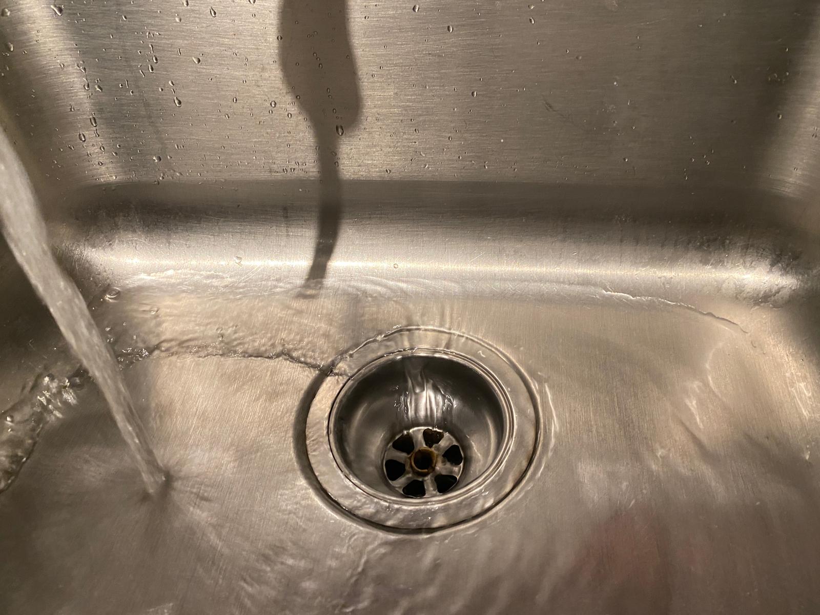 Water flowing freely down stainless steel kitchen sink drain basket, drain cleaning in Coquitlam