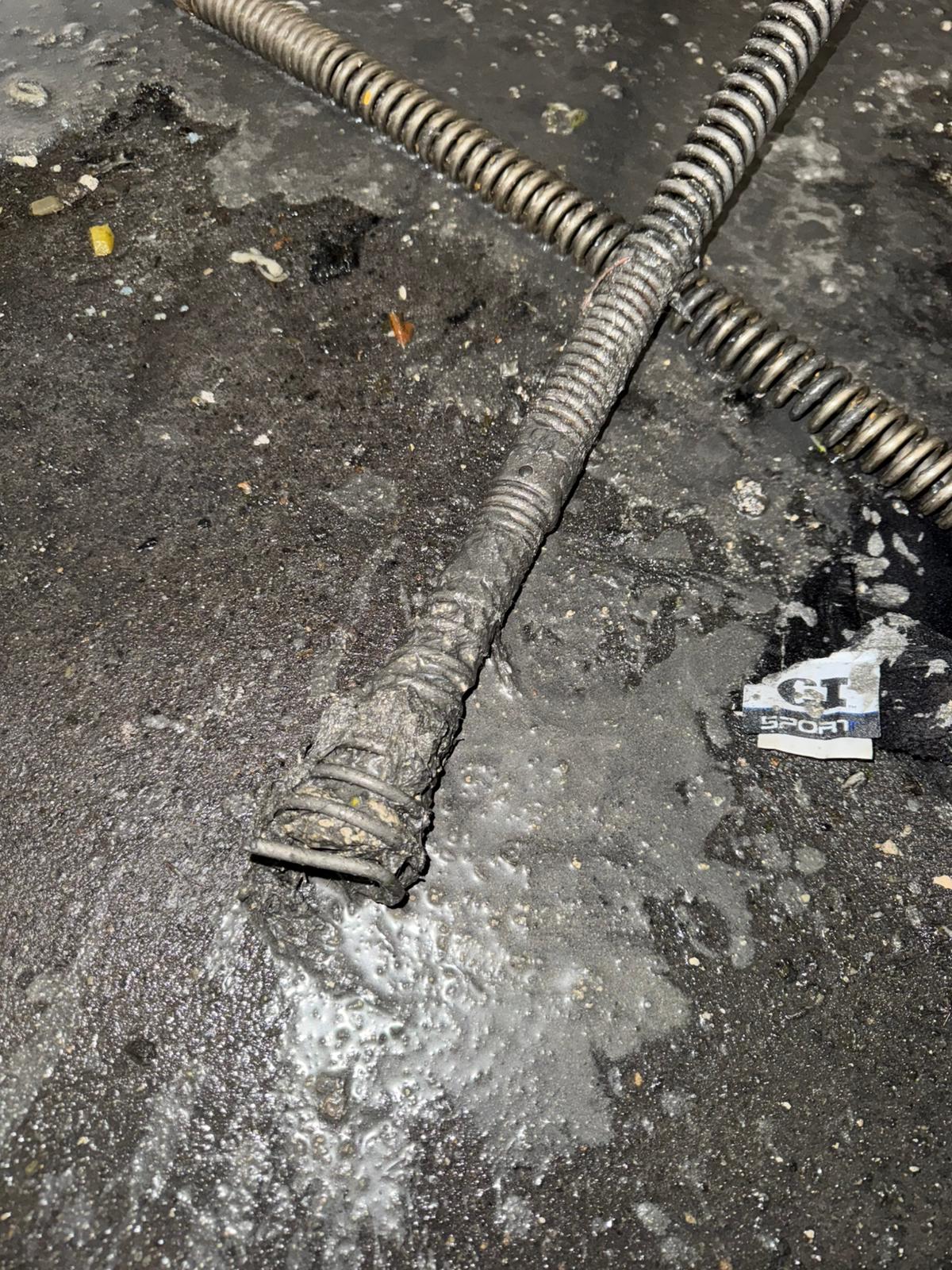 Drain snake cable entering cleanout in concrete parkade floor, commercial plumbing in Abbotsford